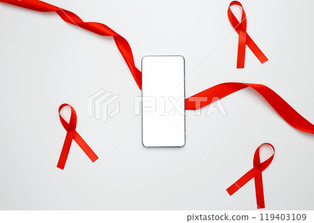 Red ribbon with AIDS awareness on a white background and a smartphone for mock up. World AIDS Day 119403109