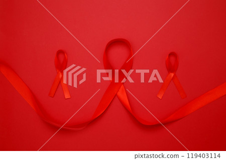 Red ribbons with awareness about AIDS on a red background. World AIDS Day 119403114