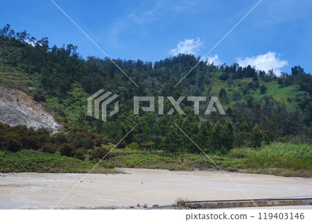 Dry lake of Telaga Warna bed with lush green hills in the background. Dry lake of Telaga Warna bed with lush green hills in the background. 119403146