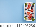 Plate with berries and mint leaves on a blue background, template for inserting text, menu. High quality photo 119403236