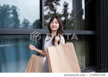 Smiling Young Woman Enjoying Shopping with Paper Bags in Modern Mall Setting 119403766