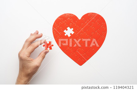 Hand holding piece near unfinished puzzle Hand holding piece near unfinished puzzle 119404321