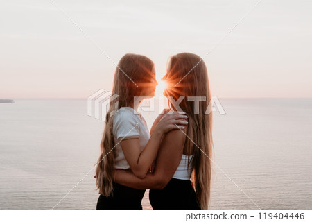 Silhouettes of Two Women Embracing at Sunset Silhouettes of Two Women Embracing at Sunset 119404446