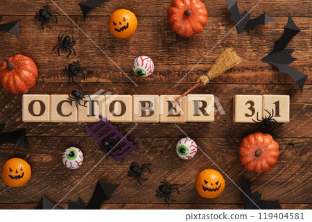 Text 31 October written with wooden cubes. Halloween vibes, pumpkins, eyes, bats, spiders, witch's broom. 119404581