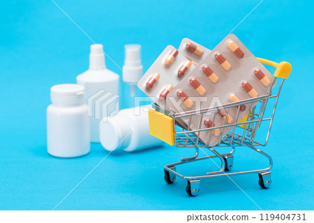 Pills and Capsules in Shopping Cart on Blue Background Pills and Capsules in Shopping Cart on Blue Background 119404731