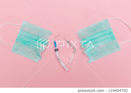Broken Medical Syringe and Torn Medical Face Mask on the Pink Background Broken Medical Syringe and Torn Medical Face Mask on the Pink Background 119404782