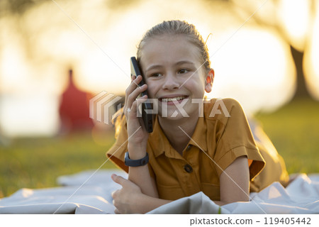 Portrait of positive happy child girl talking with her friend on cellphone 119405442