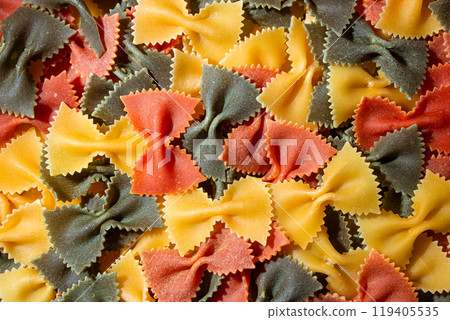 Dry Uncooked Colored Farfalle Pasta and Raw Macaroni on a Textured Background Dry Uncooked Colored Farfalle Pasta and Raw Macaroni on a Textured Background 119405535