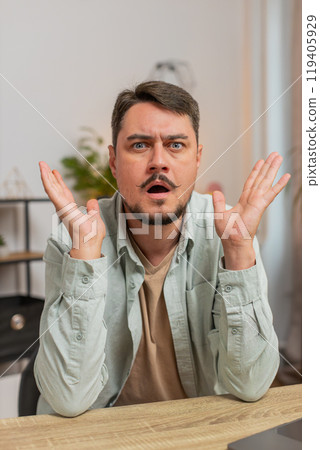 Shocked young man becoming surprised by lottery results, bad fortune, loss, unlucky news at home Shocked young man becoming surprised by lottery results, bad fortune, loss, unlucky news at home 119405929