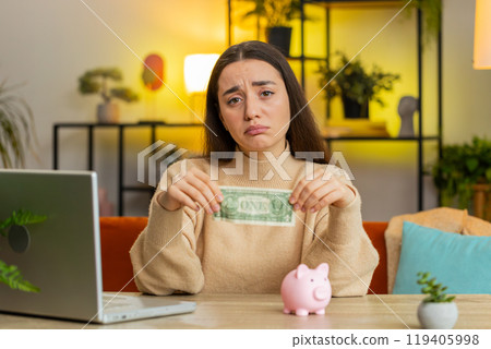 Poor Caucasian young woman holding piggybank and one dollar insufficient amount of money poverty 119405998