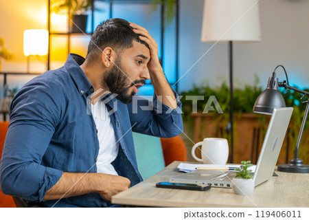 Angry furious Indian man freelancer using laptop working at home office nervous breakdown at work Angry furious Indian man freelancer using laptop working at home office nervous breakdown at work 119406011