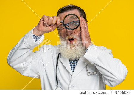 Senior doctor man holds magnifying glass near face looking at camera with big zoomed eye, analyzing 119406084