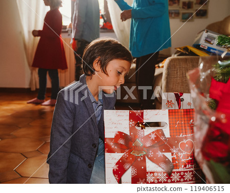 Little boy looking at presents near Christmas tree 119406515