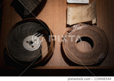 Antique film reels and Kinora projector discs displayed in a dimly lit storage box at a historical exhibit in London Antique film reels and Kinora projector discs displayed in a dimly lit storage box at a historical exhibit in London 119406584