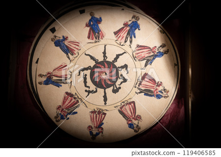 Intricate circular artwork featuring colorful figures dancing around a spiral design in a historical exhibit setting Intricate circular artwork featuring colorful figures dancing around a spiral design in a historical exhibit setting 119406585