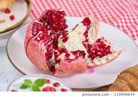 Ripe pomegranate with red seeds on a white plate 119406644
