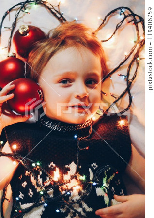 Little boy, red Christmas tree balls, burning Christmas tree garland 119406759