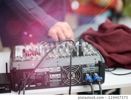 Sound Mixer with Cables and Person Adjusting Controls at Outdoor Event 119407373