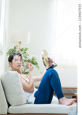 Young man putting on make-up in the living room Young man putting on make-up in the living room 119407935