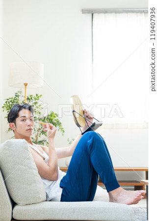 Young man putting on make-up in the living room Young man putting on make-up in the living room 119407936