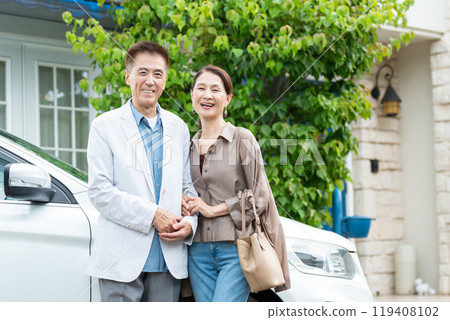 Senior couple standing together in front of a car 119408102