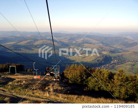 Chair lift cable car way against the backdrop of mountains and sky Chair lift cable car way against the backdrop of mountains and sky 119409185