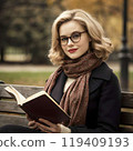 American woman reading a book on a park bench 119409193
