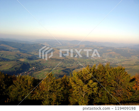 Trees in the foreground against the backdrop of landscape of autumn mountains and highland valleys 119409198