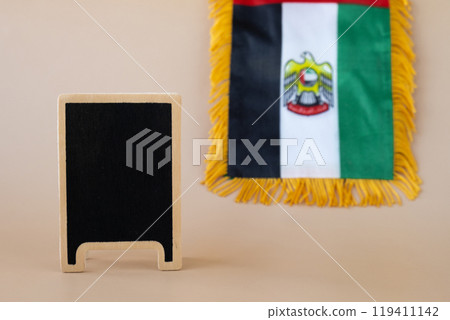 Empty blackboard template National symbol of UAE. United Arab Emirates small flag with Peregrine falcon on neutral beige background. Copy space for your text. Concept of Independence  119411142