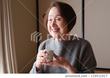 Elderly woman drinking tea in a Japanese-style room 119412917