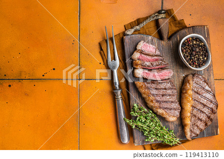 BBQ Roast brazilian Picanha steak, cup rump beef meat steak on a wooden serving board. Orange background. Top view. Copy space 119413110