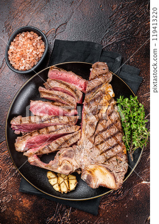 Grilled Medium rare Porterhouse, T-Bone Steak sliced in a plate. Dark background. Top view Grilled Medium rare Porterhouse, T-Bone Steak sliced in a plate. Dark background. Top view 119413220