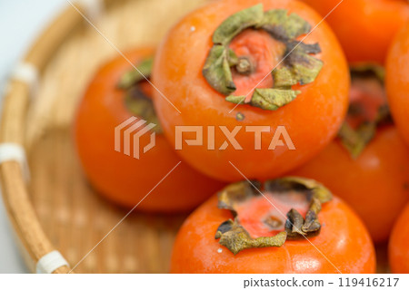 Delicious ripe persimmons in bowl on blurred background, closeup Delicious ripe persimmons in bowl on blurred background, closeup 119416217