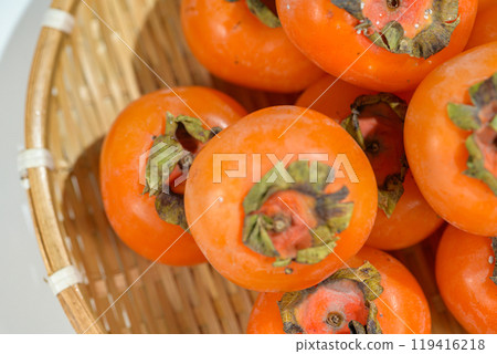 Delicious ripe persimmons in bowl on blurred background, closeup 119416218