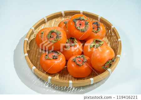 Delicious ripe persimmons in bowl on blurred background, closeup Delicious ripe persimmons in bowl on blurred background, closeup 119416221