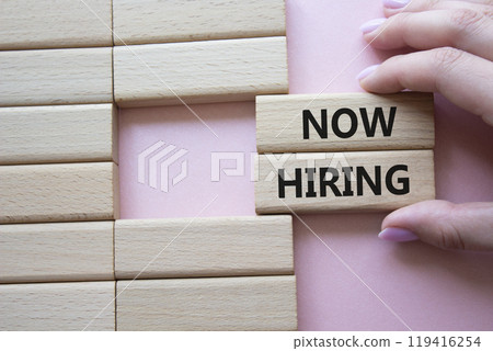 Now Hiring symbol. Concept word Now Hiring on wooden blocks. Businessman hand. Beautiful pink background. Business and Now Hiring concept. Copy space Now Hiring symbol. Concept word Now Hiring on wooden blocks. Businessman hand. Beautiful pink background. Business and Now Hiring concept. Copy space 119416254