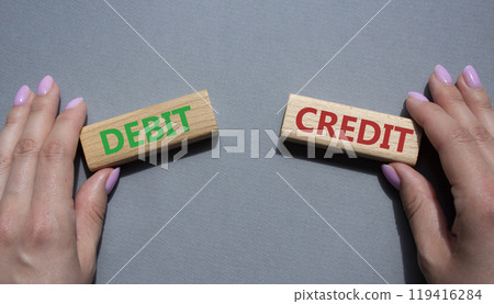 Debit or Credit symbol. Concept word Debit or Credit on wooden blocks. Businessman hand. Beautiful grey background. Business and Debit or Credit concept. Copy space Debit or Credit symbol. Concept word Debit or Credit on wooden blocks. Businessman hand. Beautiful grey background. Business and Debit or Credit concept. Copy space 119416284