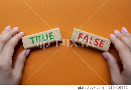 True or False symbol. Concept word True or False on wooden blocks. Businessman hand. Beautiful orange background. Business and True or False concept. Copy space 119416551
