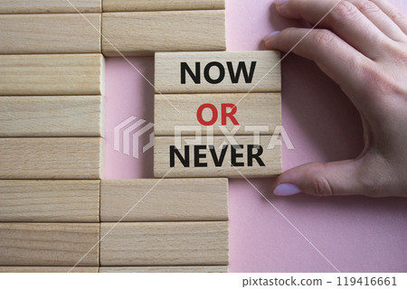 Now or Never symbol. Concept words Now or Never on wooden blocks. Businessman hand. Beautiful pink background. Business and Now or Never concept. Copy space 119416661
