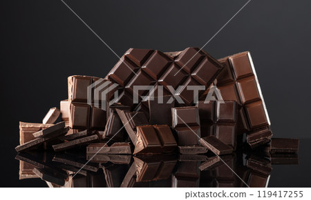 Broken bitter and milk chocolate bars on a black background. Broken bitter and milk chocolate bars on a black background. 119417255