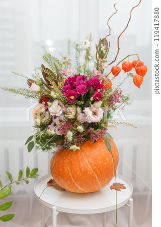 Flower arrangement in a pumpkin, autumn interior decor. Creating handmade autumn decor. 119417880