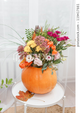 Flower arrangement in a pumpkin, autumn interior decor. Creating handmade autumn decor. Flower arrangement in a pumpkin, autumn interior decor. Creating handmade autumn decor. 119417881