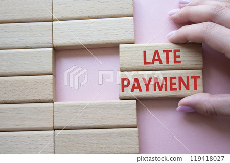 Late payment symbol. Concept word Late payment on wooden blocks. Beautiful pink background. Businessman hand. Business and Late payment concept. Copy space 119418027