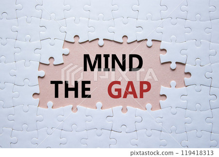 Mind the gap symbol. Concept words Mind the gap on white puzzle. Beautiful pink background with succulent plant. Business and Mind the gap concept. Copy space. 119418313