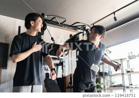 A male trainer showing training samples to members at a personal gym (chest training) 119418751