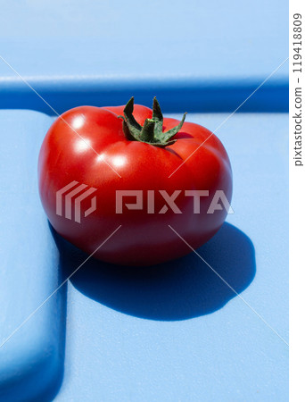 A photo of a tomato with a hard light, on an abstract blue background, for use in stylish designs about the food business 119418809