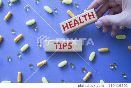 Health Tips symbol. Wooden blocks with words Health Tips. Beautiful purple background with pills. Doctor hand. Medicine and Health Tips concept. Copy space. Health Tips symbol. Wooden blocks with words Health Tips. Beautiful purple background with pills. Doctor hand. Medicine and Health Tips concept. Copy space. 119419201