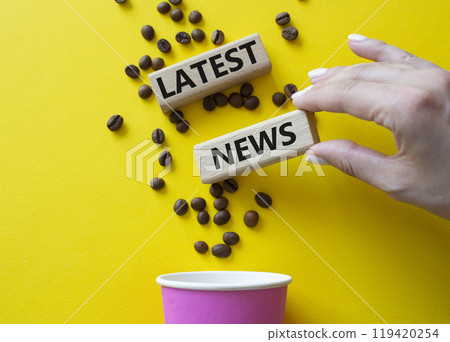 Latest News symbol. Concept word Latest News on wooden blocks. Businessman hand. Beautiful yellow background with coffee cup. Business and Latest News concept. Copy space 119420254