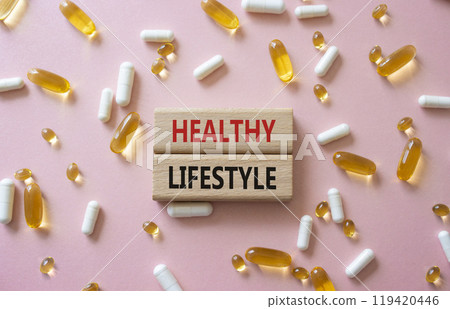 Healthy Lifestyle symbol. Concept words Healthy Lifestyle on wooden blocks. Beautiful pink background with pills. Medicine and Healthy Lifestyle concept. Copy space. 119420446