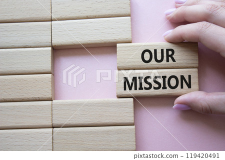 Our Mission symbol. Concept word Our Mission on wooden blocks. Businessman hand. Beautiful pink background. Business and Our Mission concept. Copy space Our Mission symbol. Concept word Our Mission on wooden blocks. Businessman hand. Beautiful pink background. Business and Our Mission concept. Copy space 119420491
